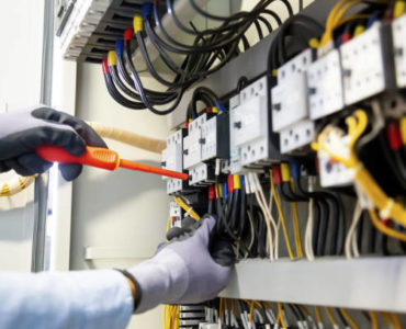 Electricians work to connect electric wires in the system, switchboard, electrical system in Control cabinet.